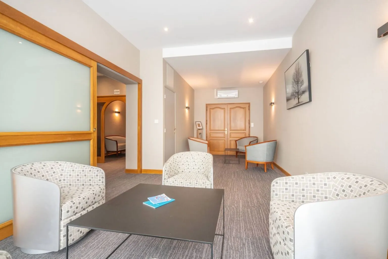Salon d'attente d'une chambre funéraire aménagé avec des fauteuils modernes et une table basse
